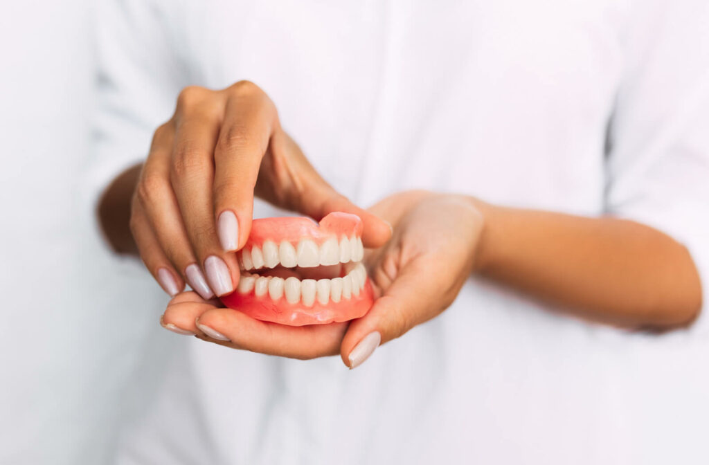 "A female dentist holding a set of dentures."