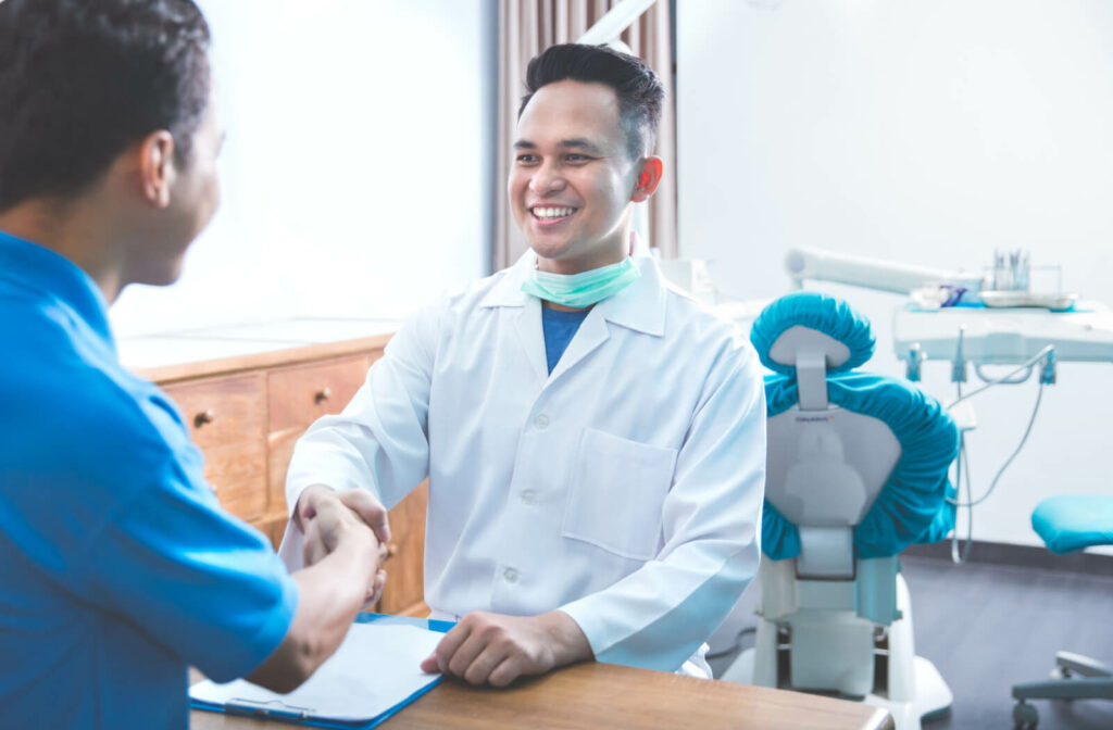 A man in an dentist's office shaking hands with his dentist