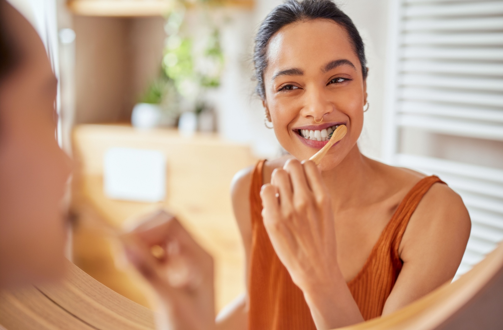 A reflection of a woman brushing her teeth.