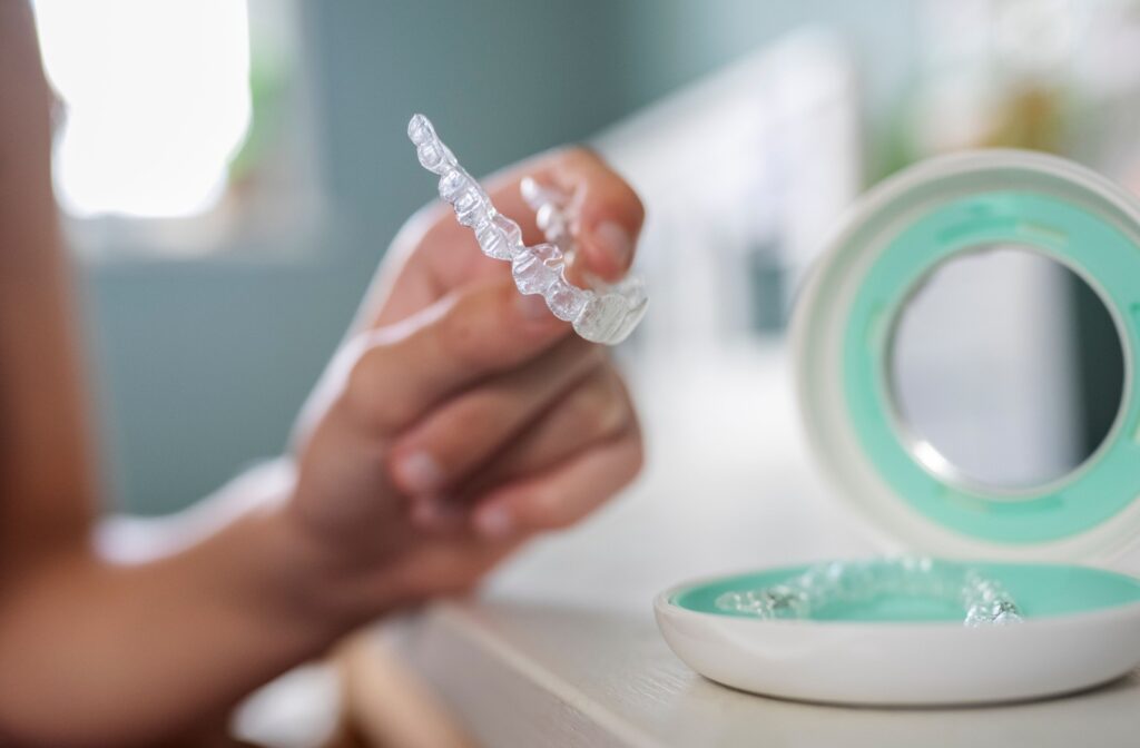 Close up of someone putting in their clear aligners from case, with focus on aligners.