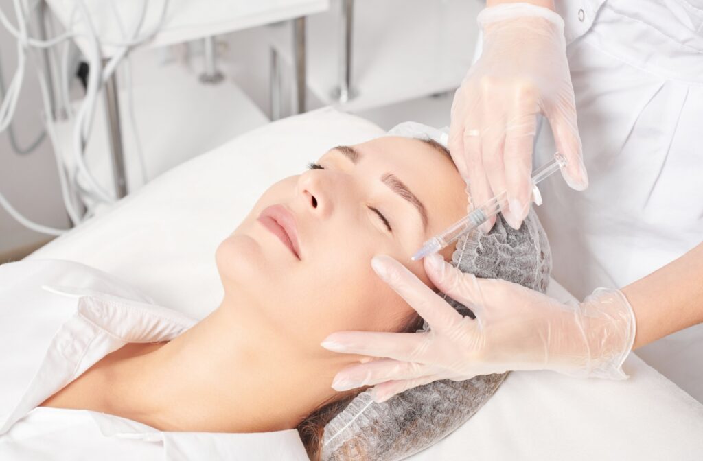 A woman receives a facial injection while lying on a treatment bed.