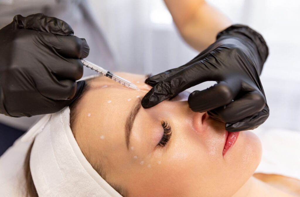Patient getting injectable into glabellar line with dots marking other places for injectables.