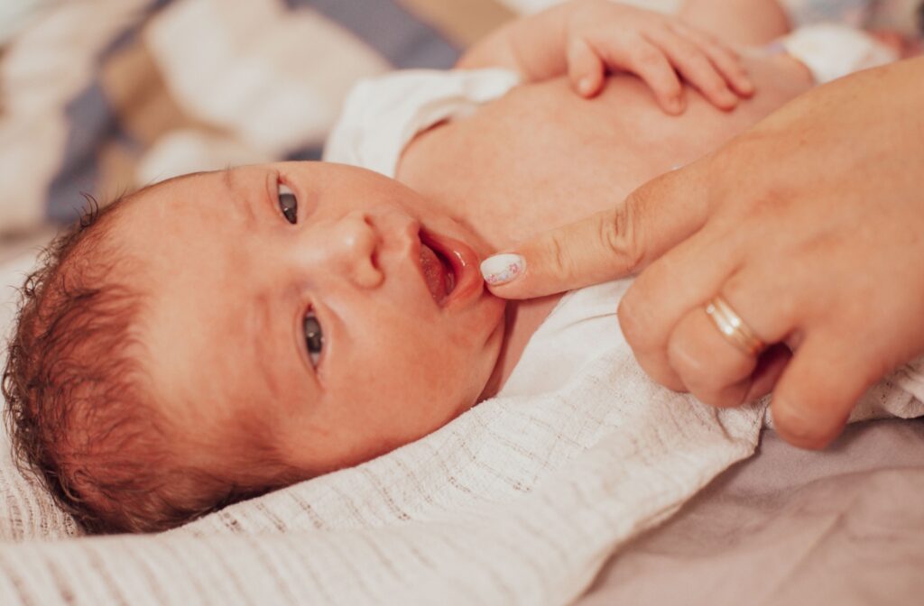A person using their finger to lower a baby's bottom lip